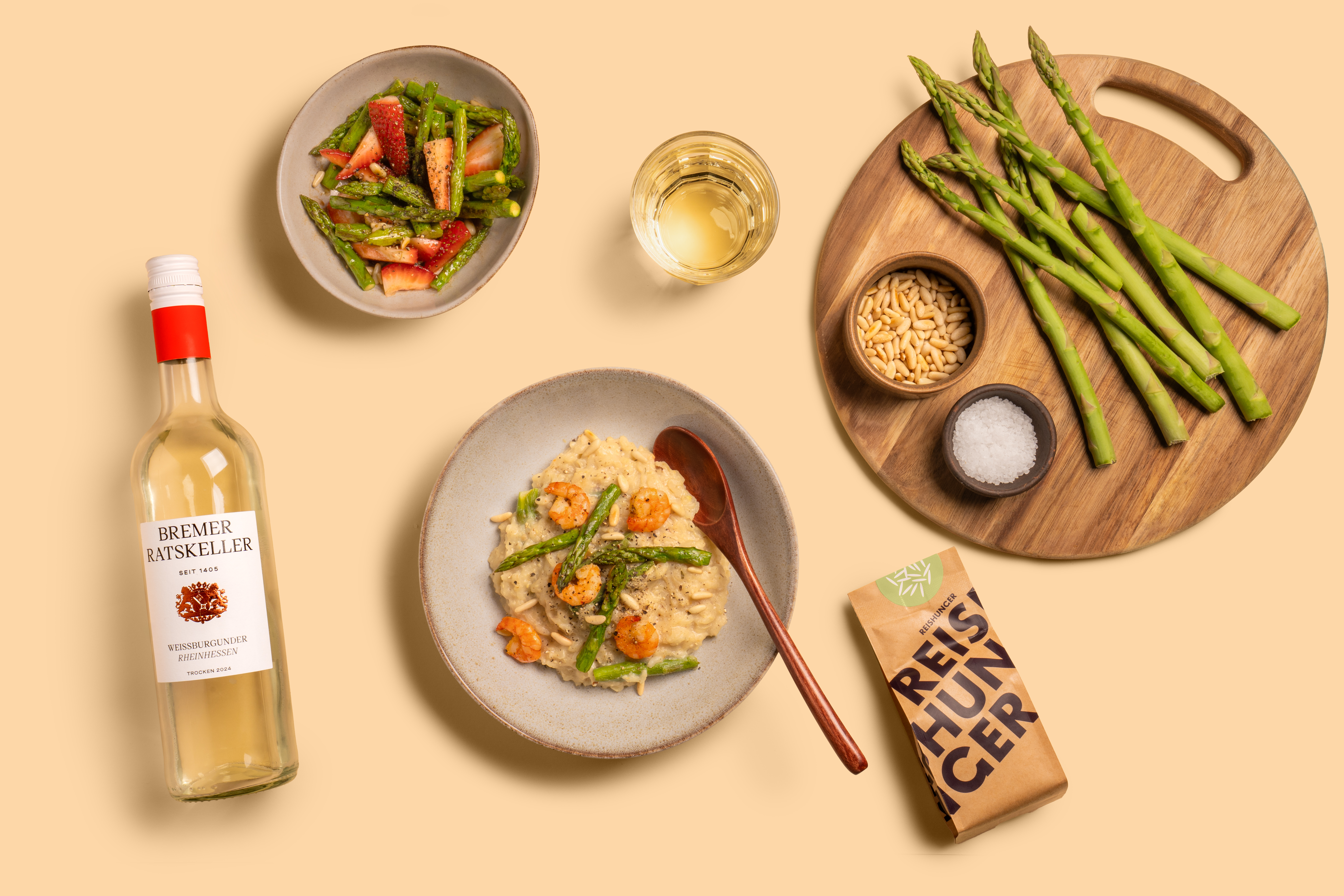 Spargelrisotto auf einem Teller mit Holzlöffel und einer Flasche Wein vom Bremer Ratskeller
